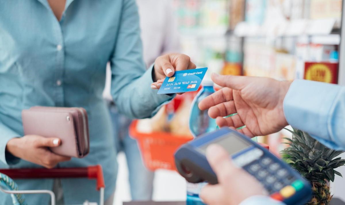 Kvinne som betaler med kredittkort i butikk.